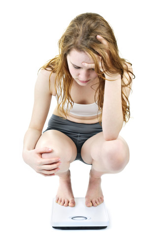 Young woman on bathroom scale worrying about her weight